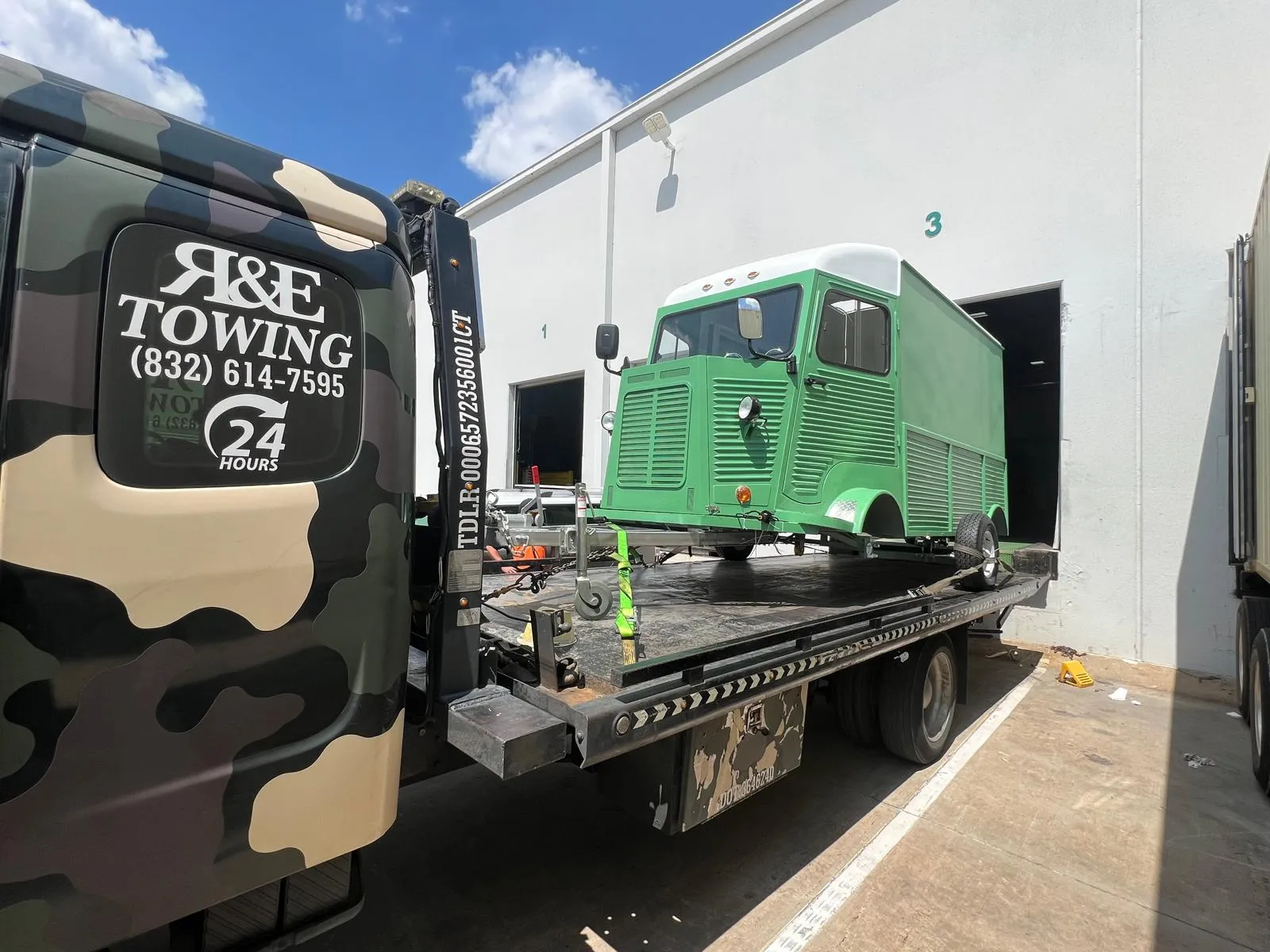 Green vintage Citroen van on flatbed tow truck for classic vehicle transport in Houston TX