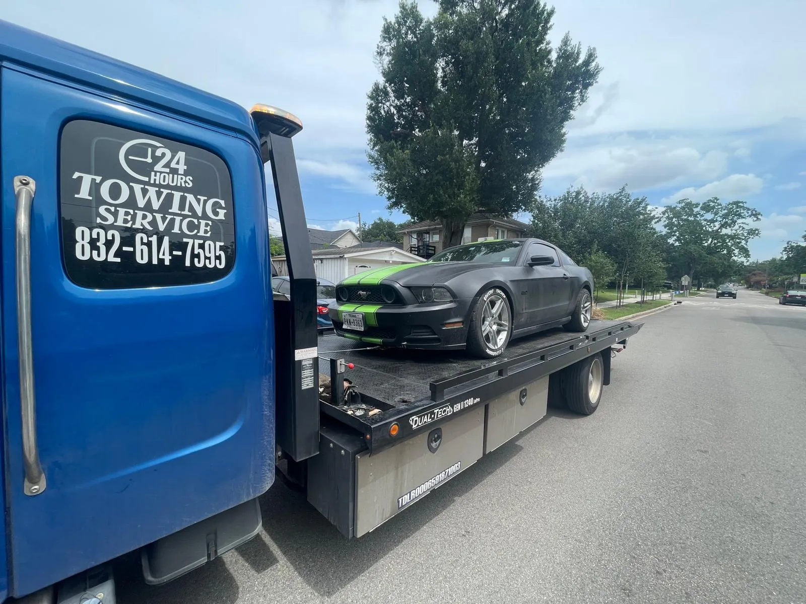 Black Ford Mustang Shelby with green stripes on flatbed tow truck in Houston TX