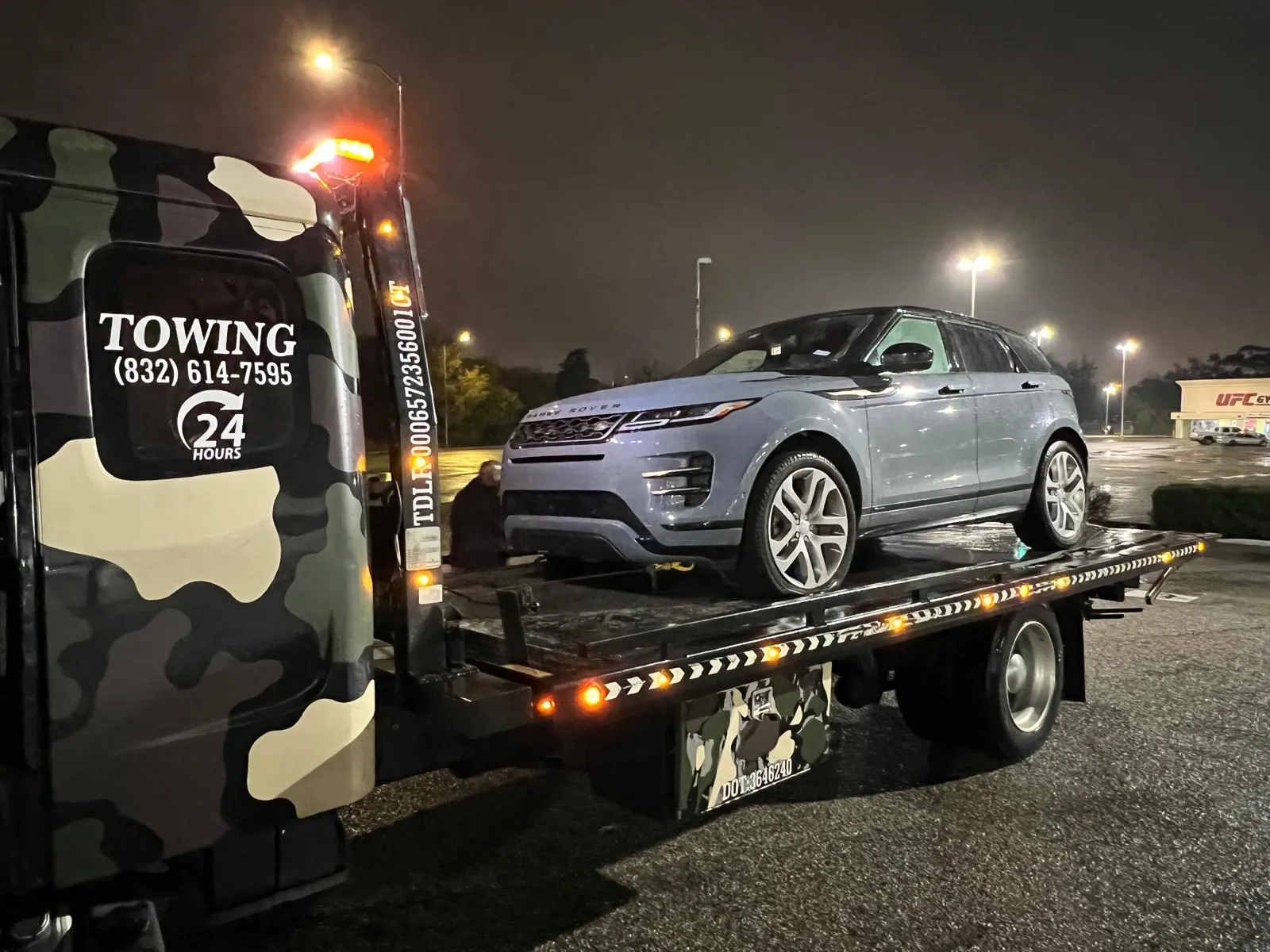 Silver Range Rover Evoque on flatbed tow truck at night in Houston TX