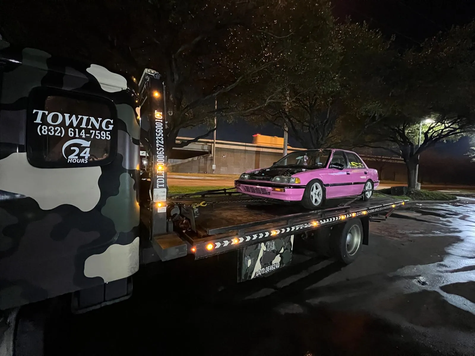 Night towing service with car on flatbed under street lights in Houston TX