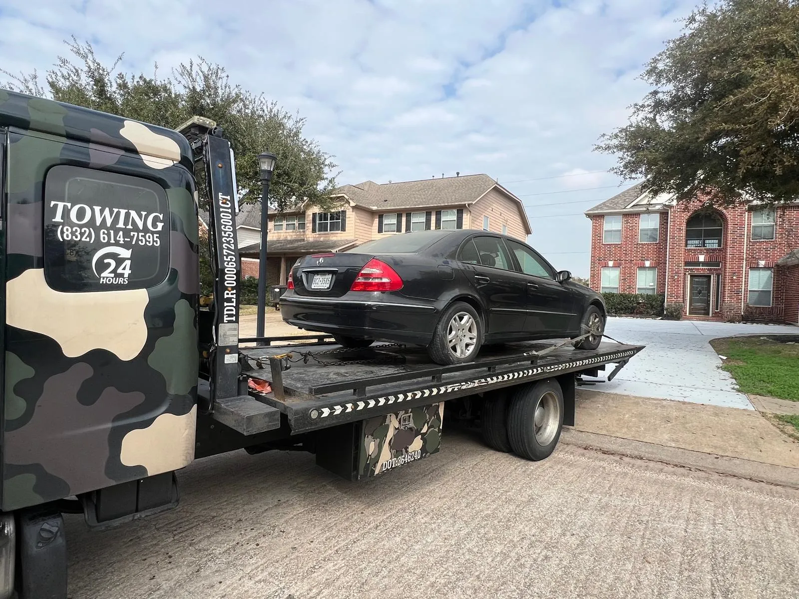 Black Mercedes sedan on flatbed tow truck at apartment complex in Houston TX