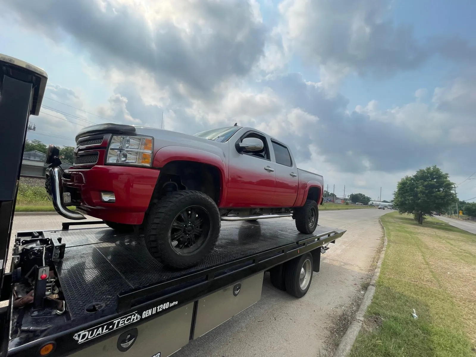 Red lifted Chevrolet Silverado on flatbed tow truck in Houston TX
